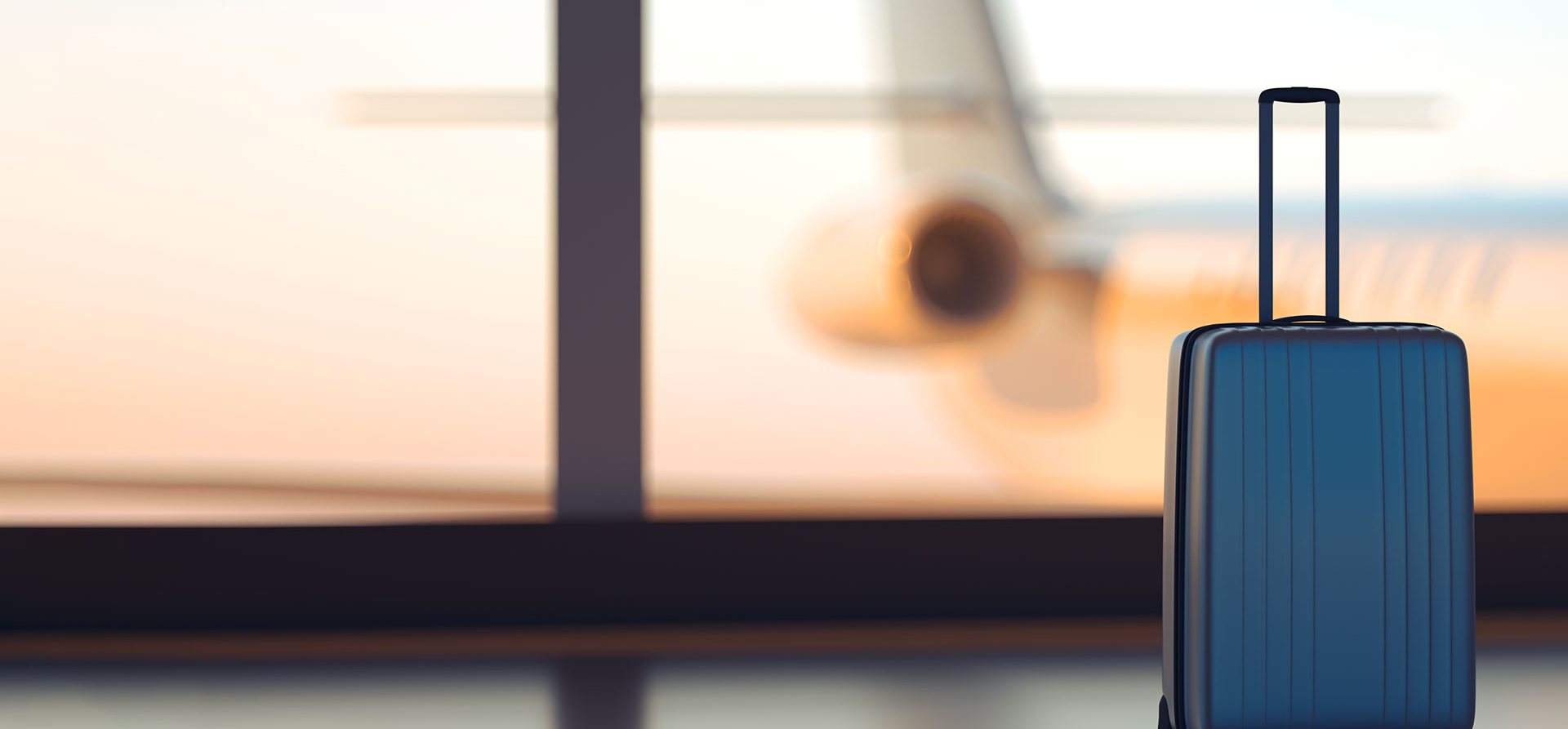 Suitcase at an airport departure gate at sunset